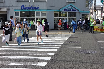 大人に見守られて横断歩道を渡る子供たちの様子