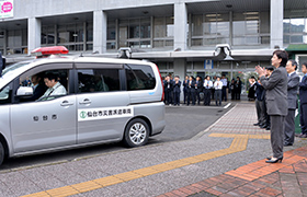 車で出発する職員を見送る市長